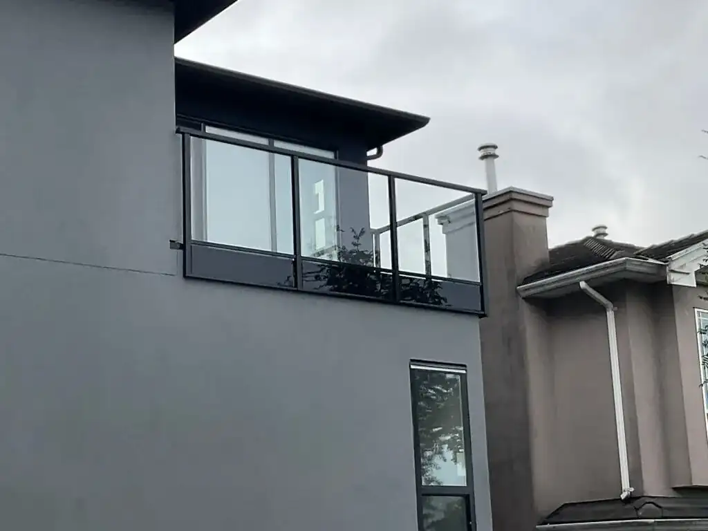 Grey house with aluminum-framed glass railings on the deck and balcony