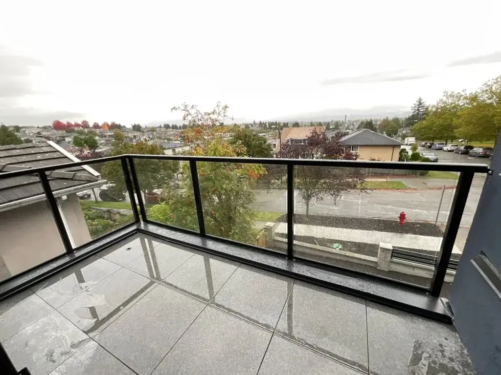 Black aluminum-framed glass railing around a balcony with a city view, installed by Alpha Glass Ltd