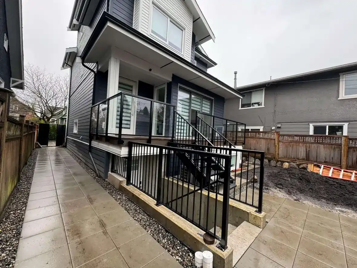 Black aluminum picket railing on an exterior stair and patio beside a new home