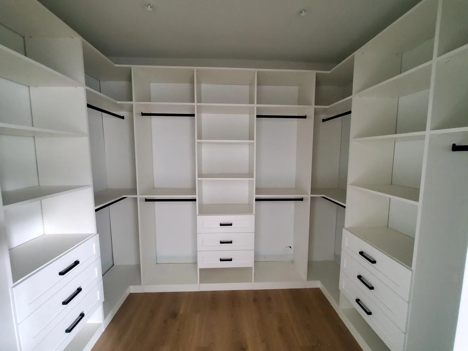 L-shaped white closet system with drawers, shelves and double hanging