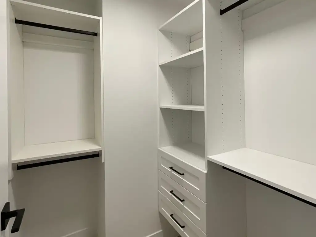 Walk-in closet with white drawers, shelves and hanging rods