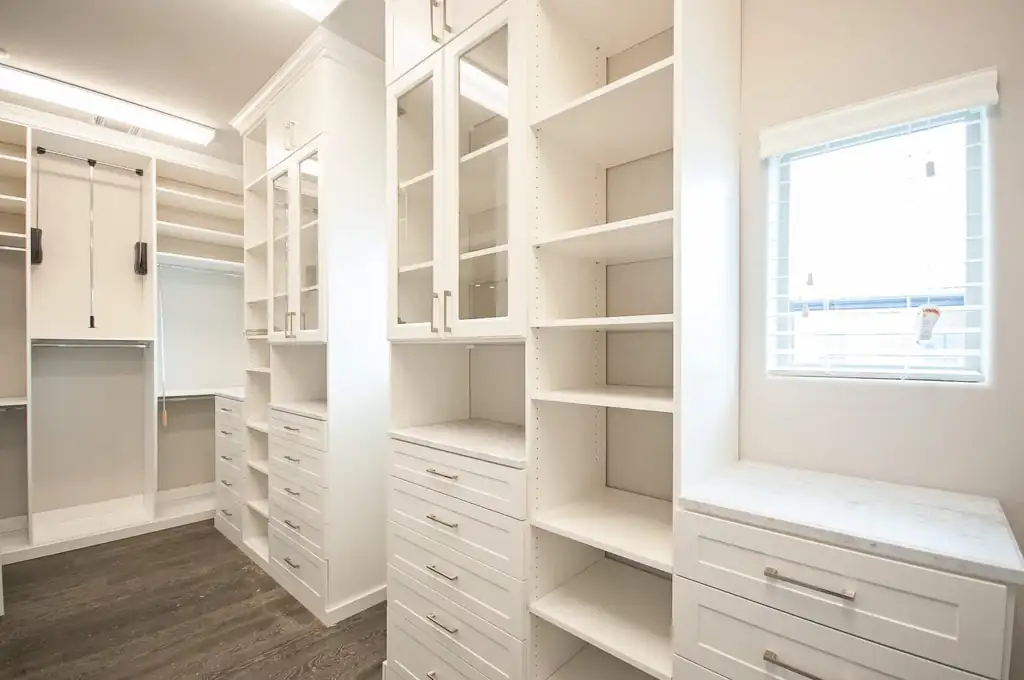 Custom white closet with glass-front upper doors and drawer banks