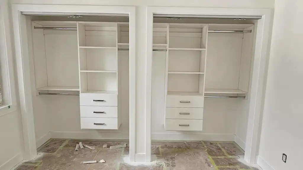 Twin reach-in closets fitted with white shelves, drawers and rods
