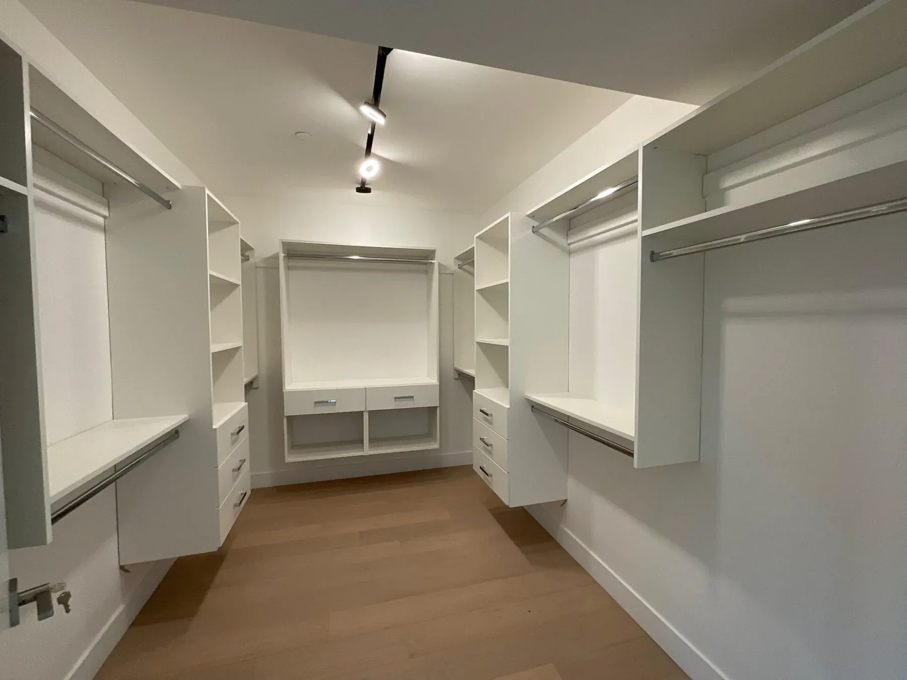White custom walk-in closet organizer with hanging rods and open shelving