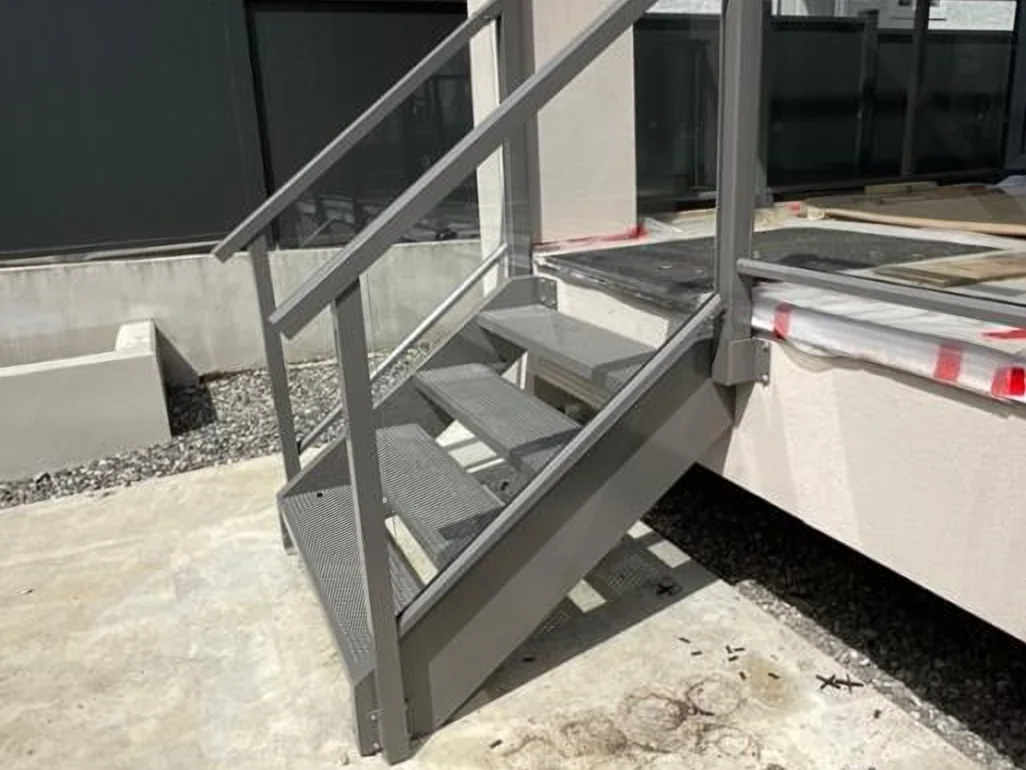 Grey aluminum stair with matching handrail at a side entrance