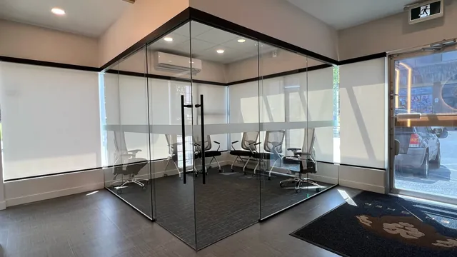 Frameless glass office corner with a black pull handle at the Tien Sher head office