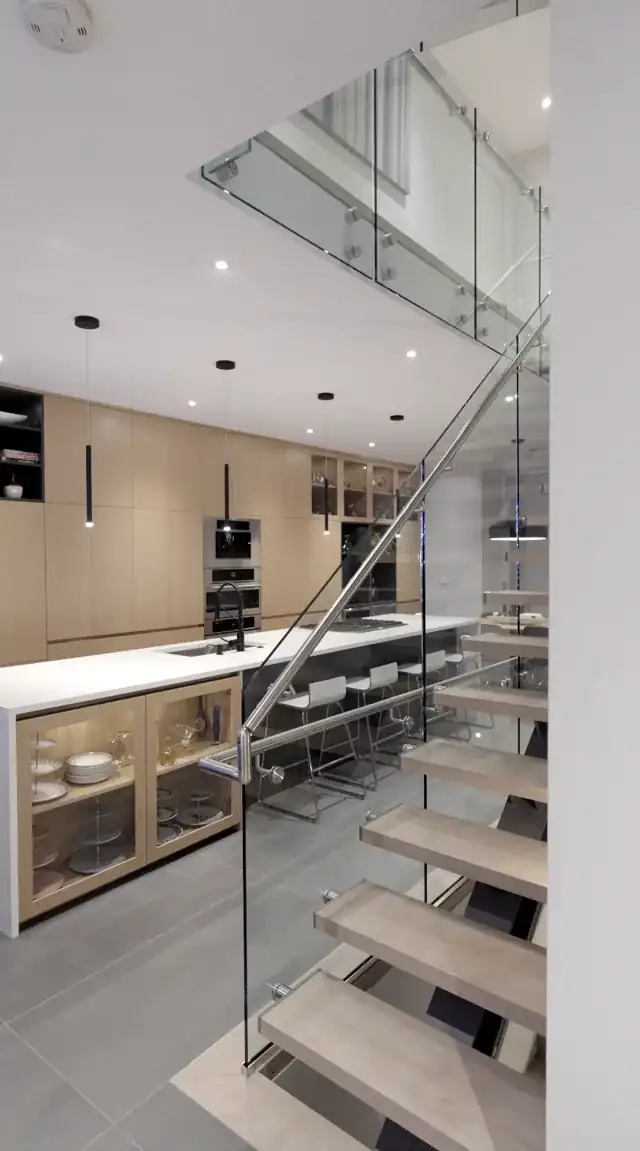 Glass stair guard running past a kitchen to the glass-guarded upper landing