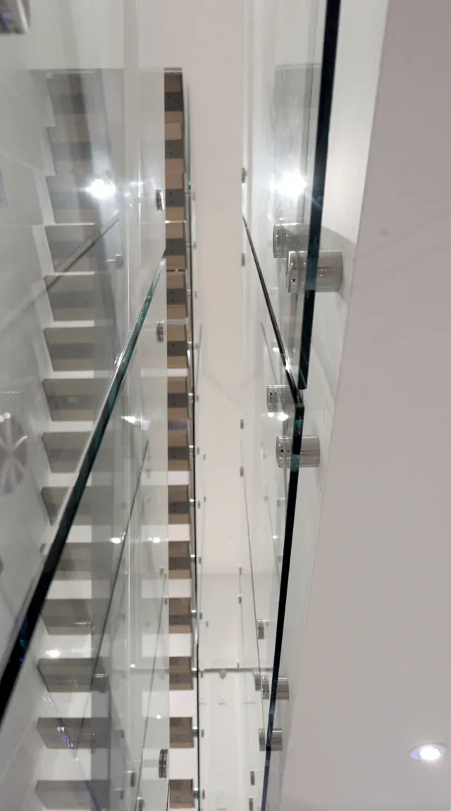 Edge-on view of the glass guard showing the standoff line up the full stair