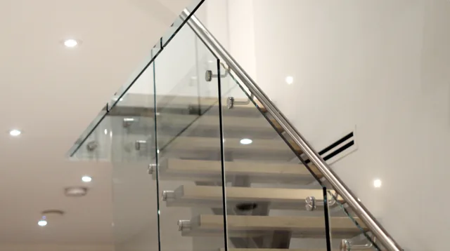Underside view of the glass guard and stainless handrail following the stair