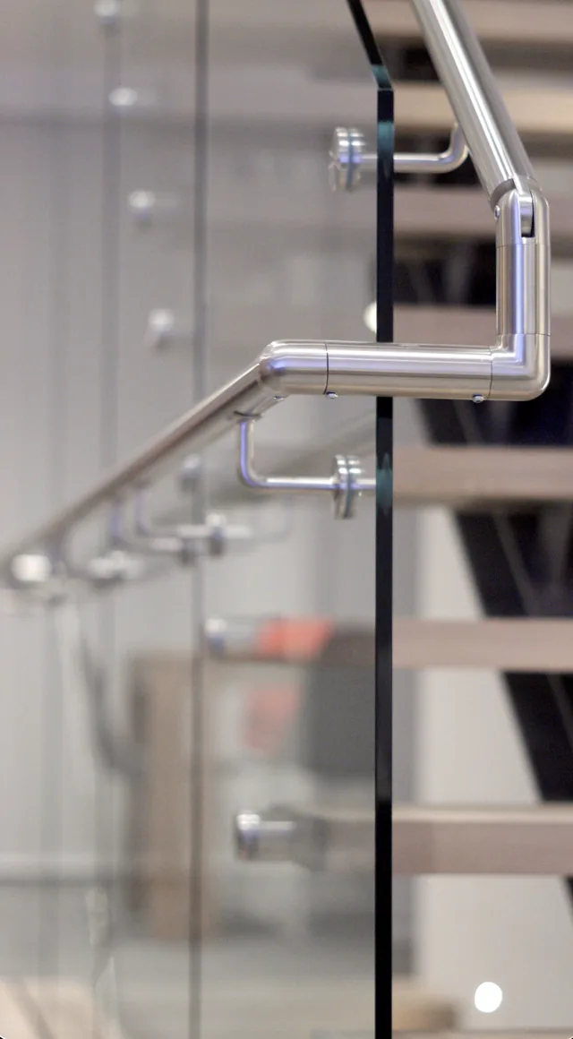 Stainless handrail returning around the glass on glass-mount brackets