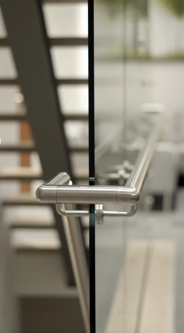 Stainless handrail return and bracket detail at the base of the stair