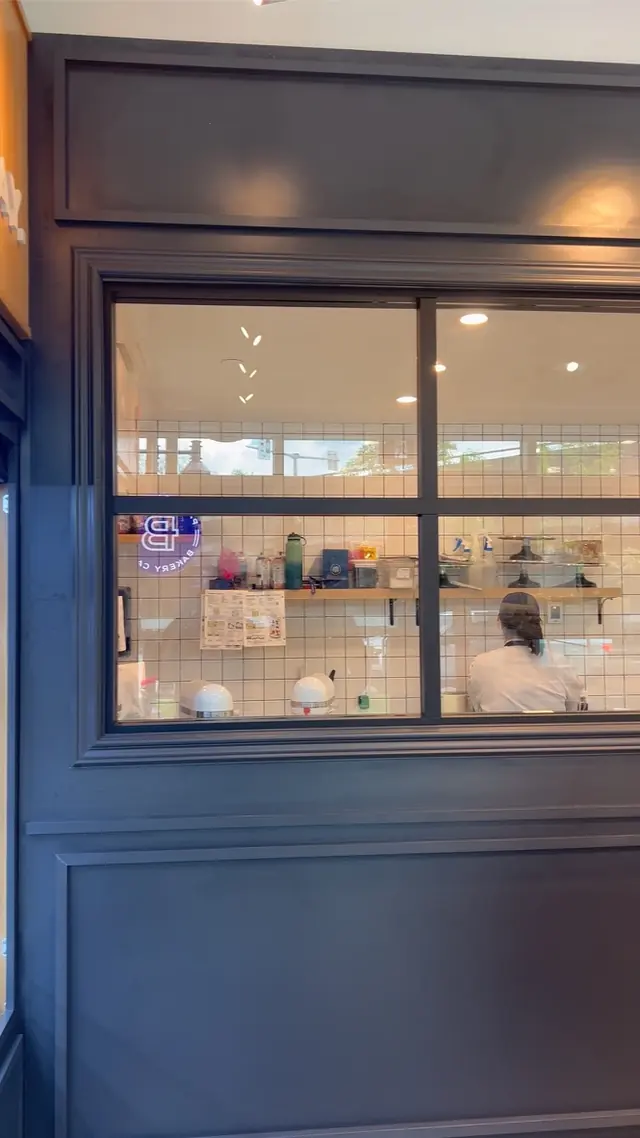 Black-framed interior glass partition set into a navy panelled wall at Paris Baguette