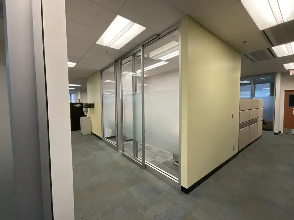 Frameless glass office partitions with switchable smart film along an open-plan corridor