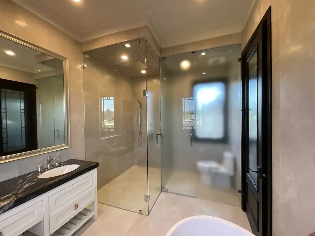 Ensuite bathroom with a glass shower enclosure fitted with switchable smart film