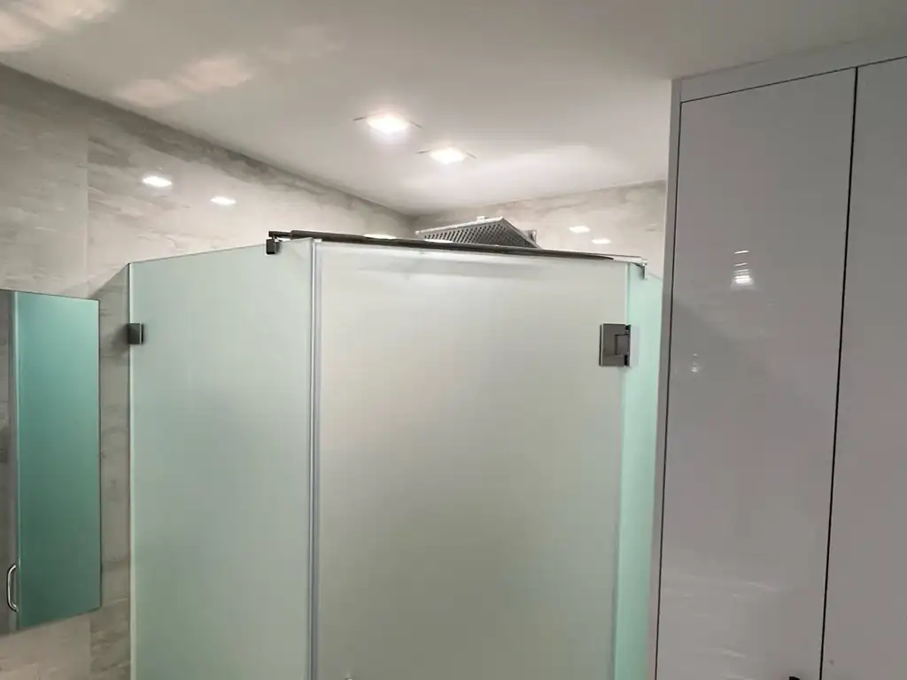 Corner glass shower enclosure with smart film glass in the opaque setting